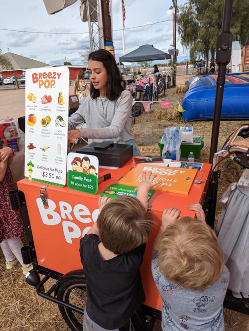 Children buying ice pops from a vendor cart at the festival.